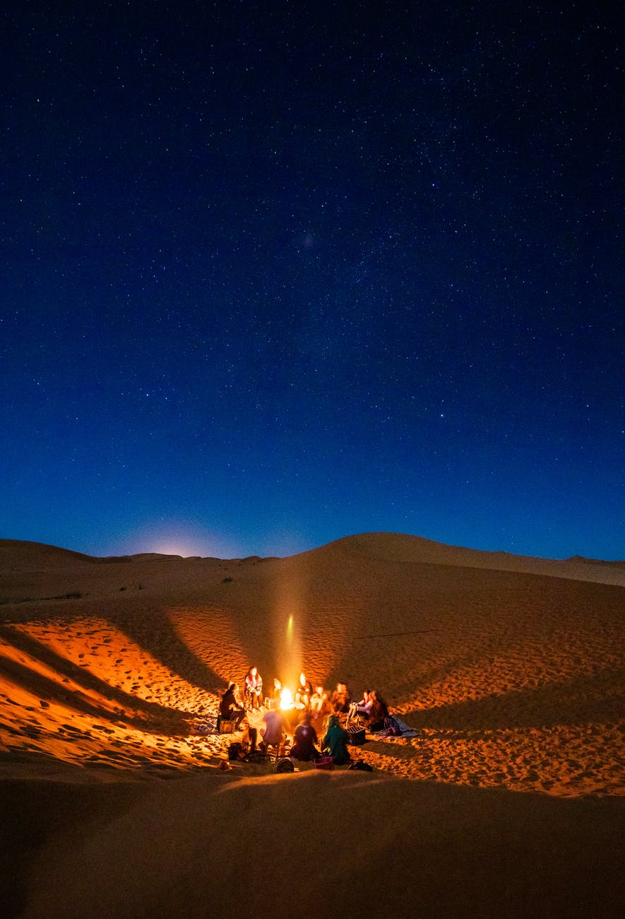 people sitting in front of bonfire in desert during nighttime