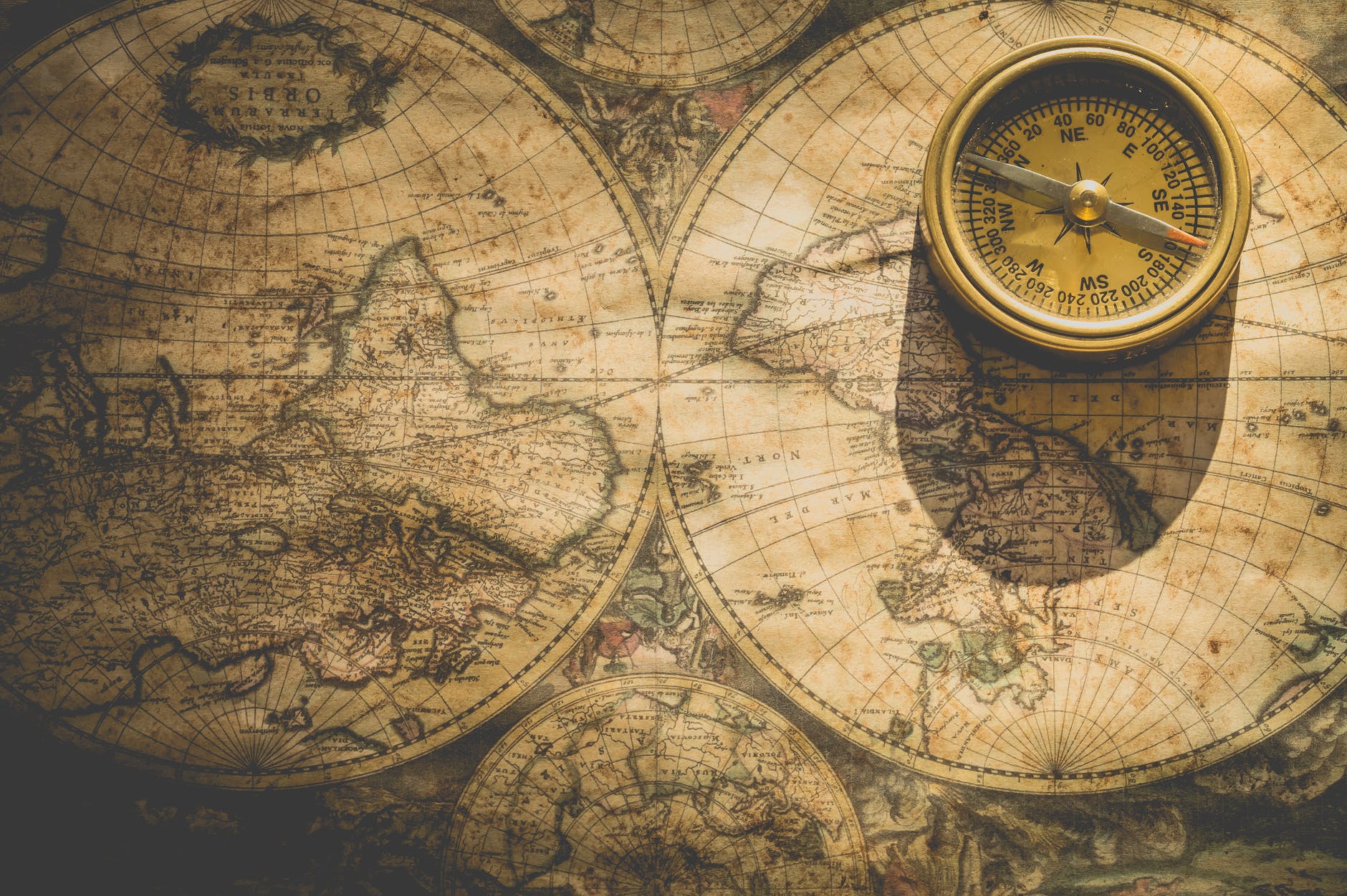 An antique compass resting on an old map, featuring intricate details and geographical outlines.